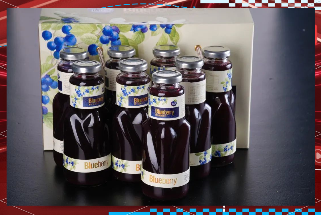一张展示桌上摆放着多种蓝靛果加工产品:玻璃瓶装深蓝色果汁、透明袋装冻干蓝靛果颗粒、塑料罐装蓝靛果果酱、铝箔小包装粉末冲剂,背景为现代化食品加工厂内部 蓝靛果深加工产品展示