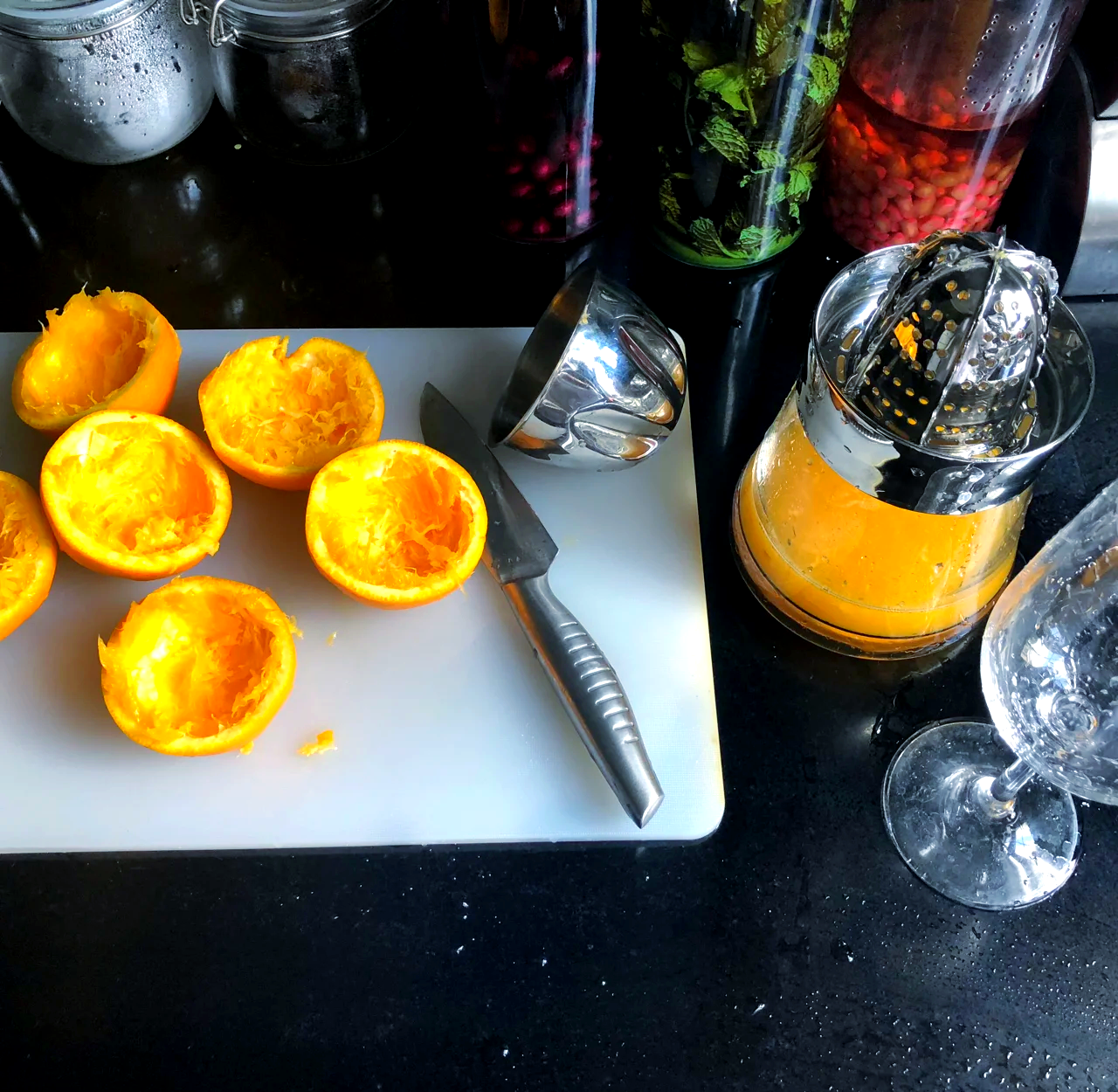 一个明亮现代的厨房场景,展示甜橙在日常生活中的多种用途:新鲜切片、榨成果汁、用于制作沙拉,体现其在饮食中的多功能性 厨房台面上摆放着切开的甜橙、玻璃杯中的橙汁以及用橙子装饰的沙拉盘