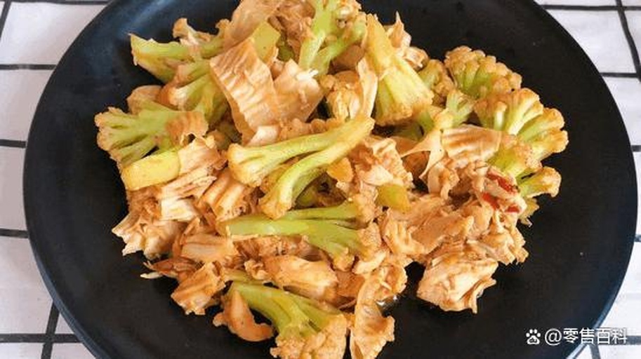 俯拍视角:青翠西兰花与米白色豆皮条交错铺满白瓷圆盘,表面淋着琥珀色酱汁,点缀鲜绿葱花与莹白芝麻;酱汁均匀附着无水渍,西兰花花蕾清晰饱满,豆皮条柔韧舒展,呈现专业餐厅级摆盘质感 西兰花与豆皮凉拌完成装盘特写