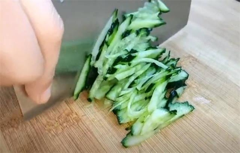 俯拍实景:左侧操作台放置洗净黄瓜1根、不锈钢削皮器、玻璃碗(内盛切好的细丝)、计时器显示'00:00';右侧操作台放置苦瓜1根、锋利厨刀、小勺(用于挖瓤)、带刻度量杯(盛清水用于浸泡去苦)、计时器显示'02:17'。两台面均铺浅灰麻布,自然光照明。 家庭厨房场景中黄瓜与苦瓜备餐对比