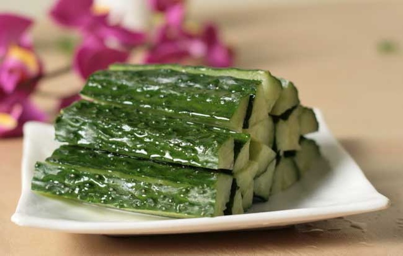 高清静物摄影:成品菜呈现理想质地对比——黄瓜片保持半透明脆感,香菜叶边缘微卷显新鲜度,油醋汁未沉底而呈悬浮乳化状,体现优质农产品与科学工艺结合效果 盛装完成的双翠沁凉汁特写:浅青色黄瓜片与墨绿色香菜叶在透明玻璃碗中层次分明,芝麻油形成均匀光泽膜,表面浮散金黄熟芝麻与微褐蒜末,碗沿凝结细微水珠显示低温保鲜状态