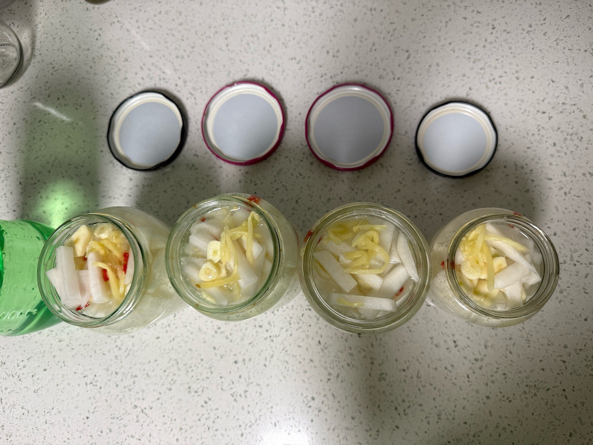 玻璃罐中浸泡着粉白色萝卜片的腌菜特写