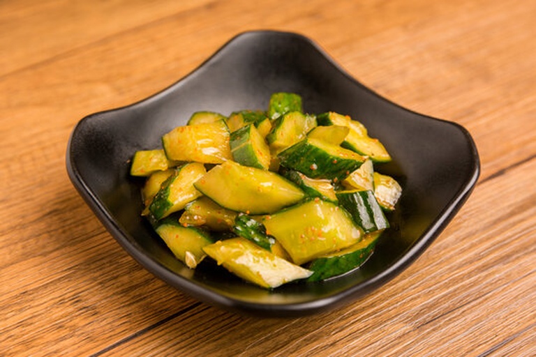 一张摆放在木质餐桌上的晚餐盘,包含切片小黄瓜拌木耳、柠檬汁调味,旁边配有全麦面包和一杯温水,整体呈现健康轻食风格,灯光温馨 晚餐中的小黄瓜料理