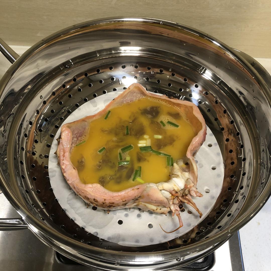 一个白色圆形蒸碗中盛着刚出锅的鸡蛋蒸螃蟹,金黄色的蛋羹包裹着红褐色的蟹块,表面光滑无孔,热气腾腾,旁边配有筷子和小勺 图片描述