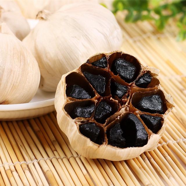 黑蒜与鲜蒜对比特写:展示正常发酵黑蒜的健康色泽与质地,区别于腐败变质 黑蒜与鲜蒜对比特写:左侧为光泽油润、饱满紧实的成熟黑蒜瓣(深棕近黑,表面微泛琥珀光泽),右侧为洁白饱满的新鲜紫皮大蒜瓣;两者并排置于竹制托盘上,背景为浅木纹台面