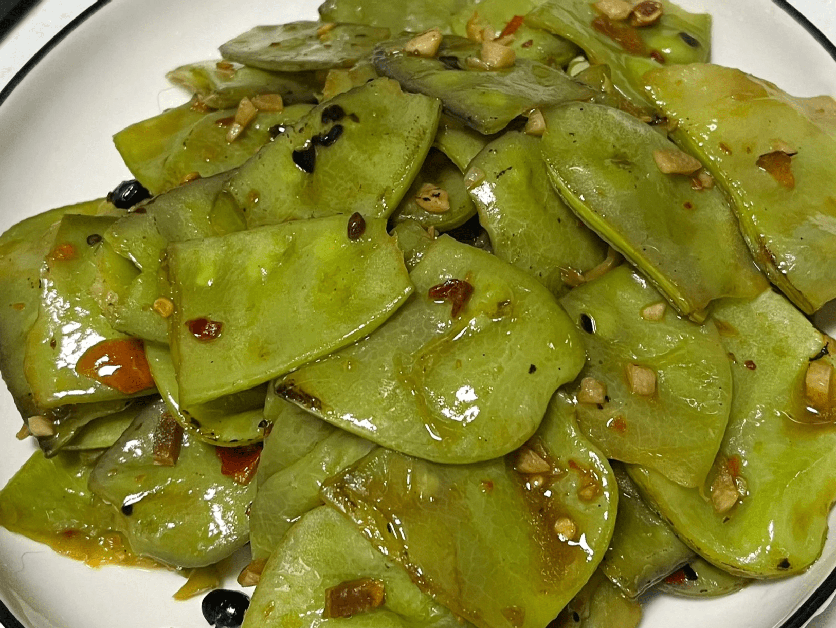 专业厨房实拍：不锈钢炒锅中绿扁豆与蒜末同炒，豆荚保持鲜翠欲滴色泽，锅气升腾但无焦糊，计时器显示1分50秒