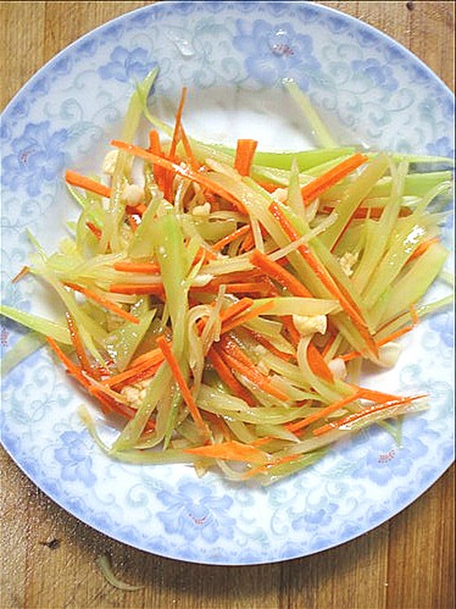 成品菜特写：青翠黄瓜片、亮橙胡萝卜丝、嫩绿芹菜段在浅褐色油光中分明呈现，撒有白芝麻与少许枸杞，盛于青瓷浅盘