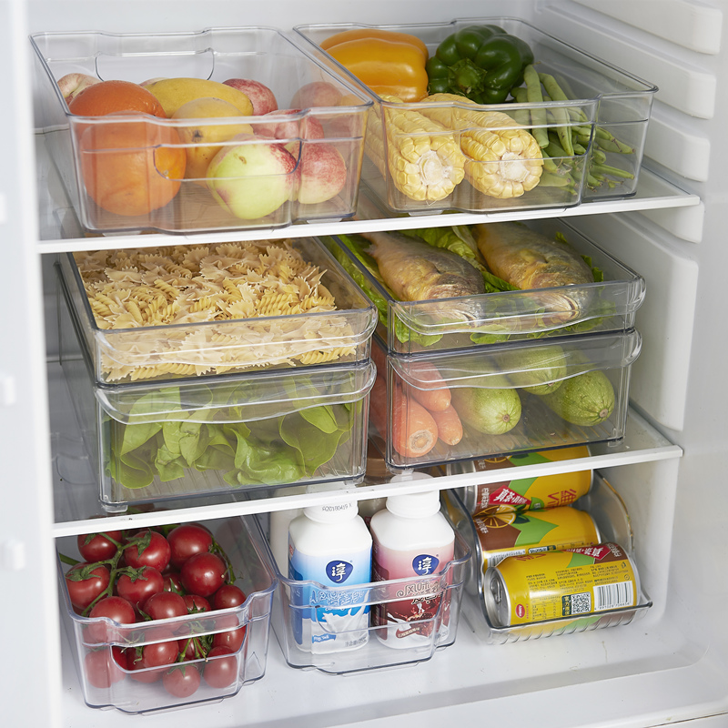 冰箱保鲜抽屉中整齐摆放着几串用保鲜膜 loosely 包裹的葡萄，周围有少量绿叶衬托