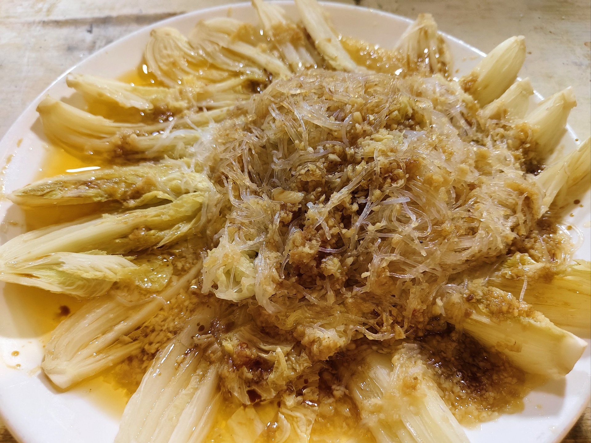 一道完成的蒜蓉粉丝蒸娃娃菜,白色细粉丝铺底,上面整齐摆放已蒸熟的嫩黄色娃娃菜条,表面覆盖金黄蒜蓉,点缀青葱末,盘边有轻微蒸汽升腾,展现家常美味佳肴 蒸好的蒜蓉粉丝娃娃菜成品图