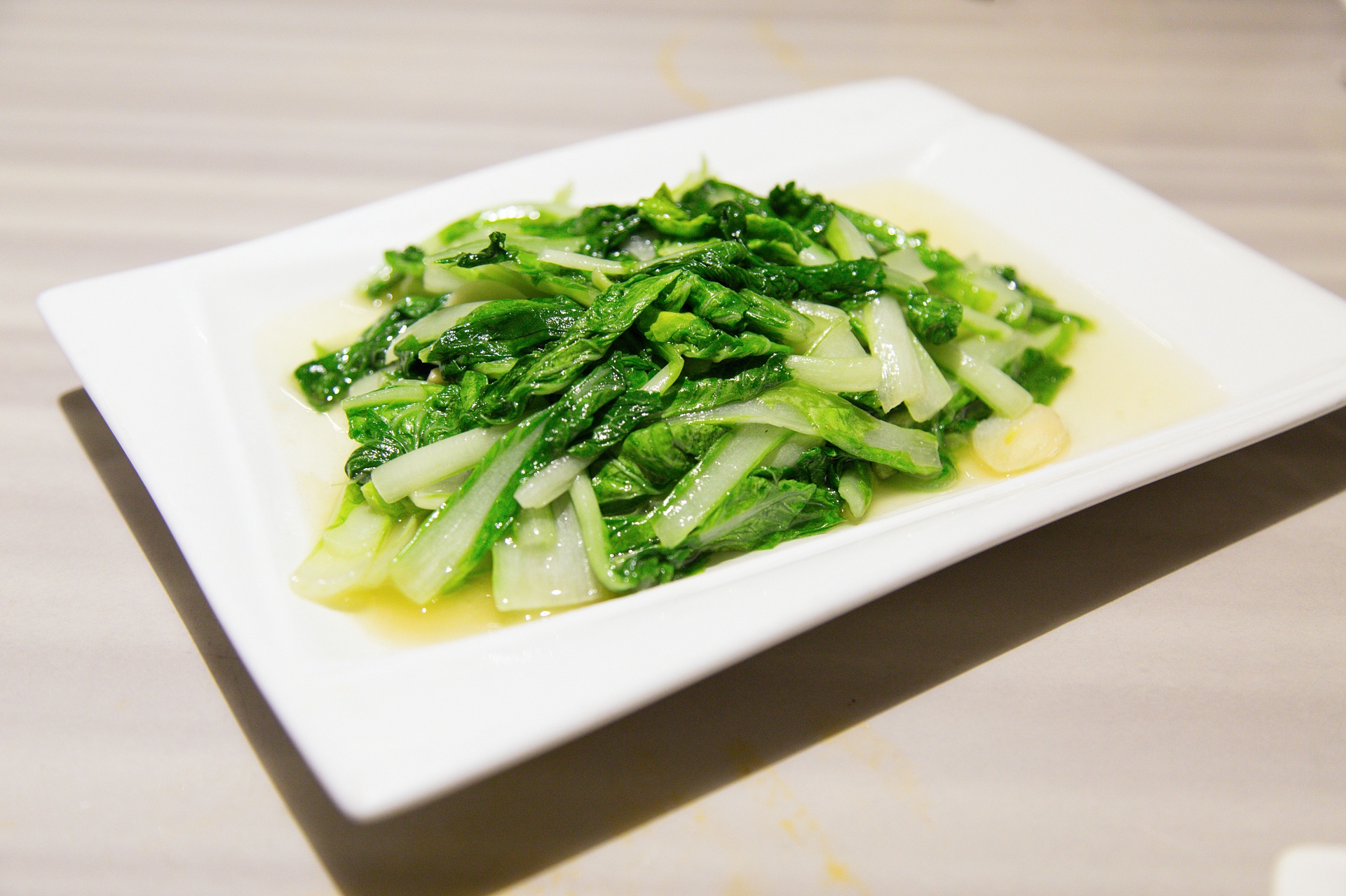 小油菜清蒸特写：翠绿菜叶完整舒展，茎部半透明，盘底无多余水分，蒸汽余韵可见