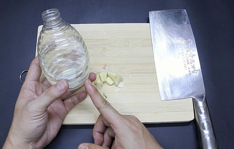 高清微距图:展示传统手动去皮法——用拇指与食指合力按压蒜瓣基部,利用内部气压使蒜衣自然松脱;背景为木质砧板,蒜皮呈半透明浅褐色卷曲状散落 手部特写:三指捏住一瓣带皮大蒜,指尖轻压蒜瓣底部,蒜衣已微微鼓起翘边