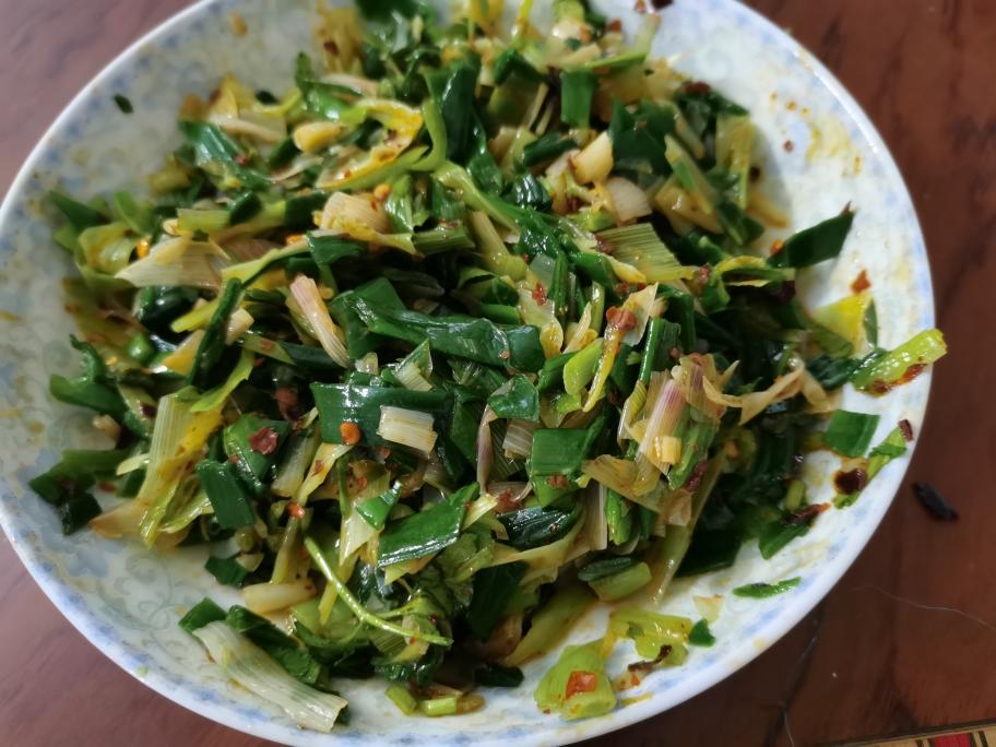 厨房场景：不锈钢炒锅中韭菜快炒过程抓拍，油花轻微溅起，韭菜呈鲜亮翠绿色，锅边放置计时器显示'01:15'，旁置温度计显示油温118℃