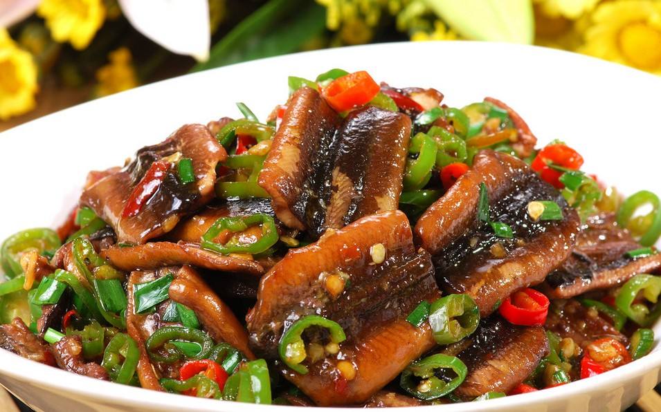 厨房操作台上整齐摆放着处理好的黄鳝段、切成段的翠绿蒜苗、姜片、蒜瓣、干辣椒等烹饪所需全部食材,背景为干净整洁的中式灶台 食材摆盘图