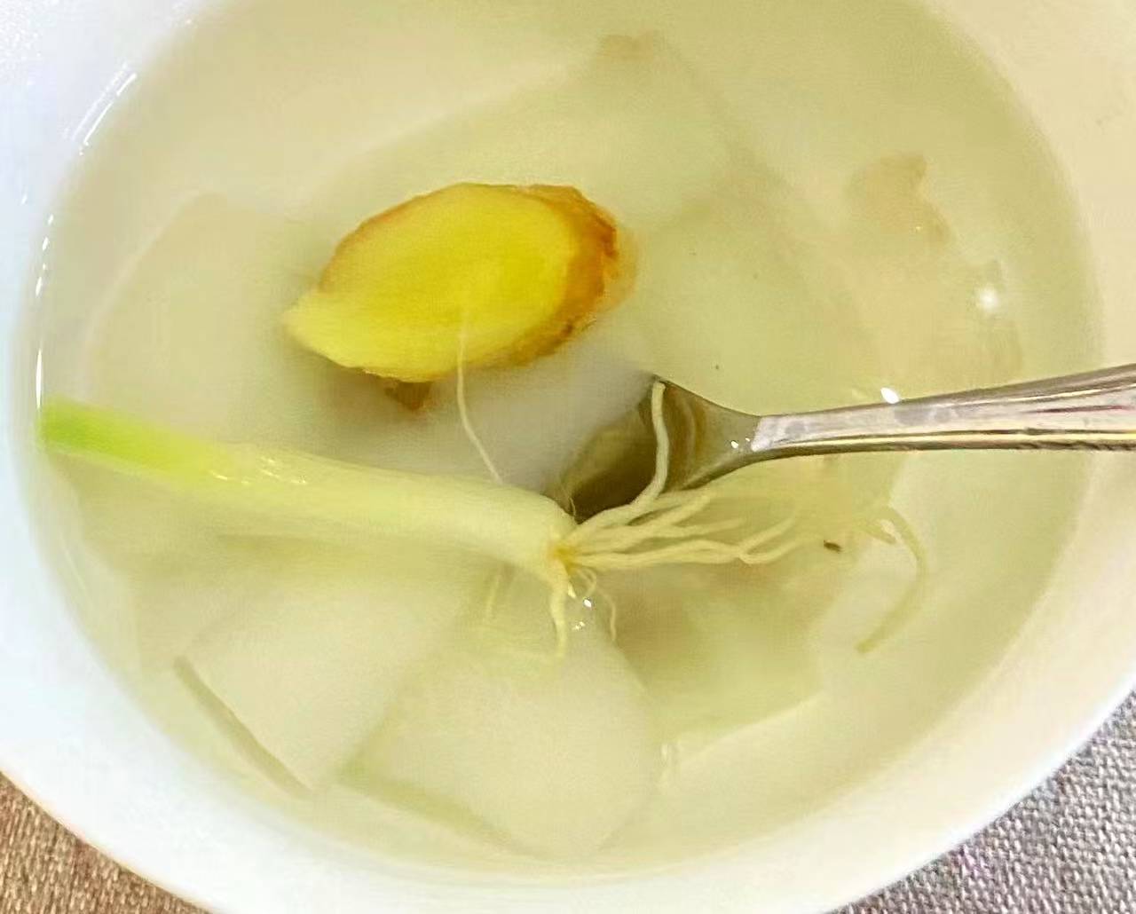 煮好的葱须白萝卜水倒入瓷杯中特写