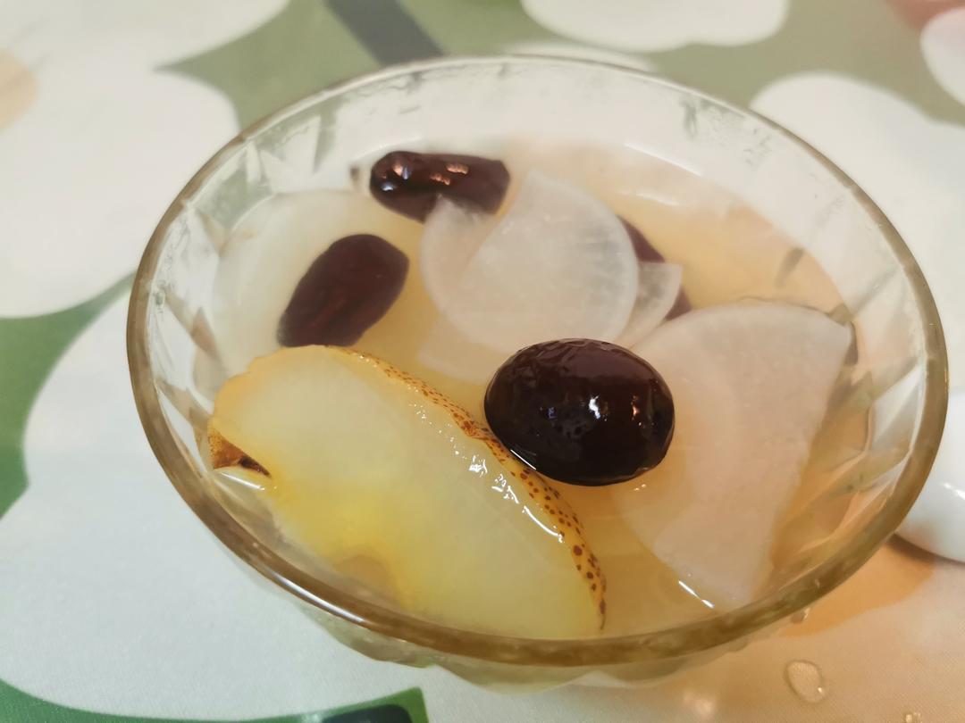 一碗刚出锅的水晶梨炖冰糖摆放在浅灰色餐垫上,梨肉呈半透明状,汤色清澈微黄,旁边配有银色小勺,背景虚化,营造温馨养生氛围 成品水晶梨炖冰糖盛盘图