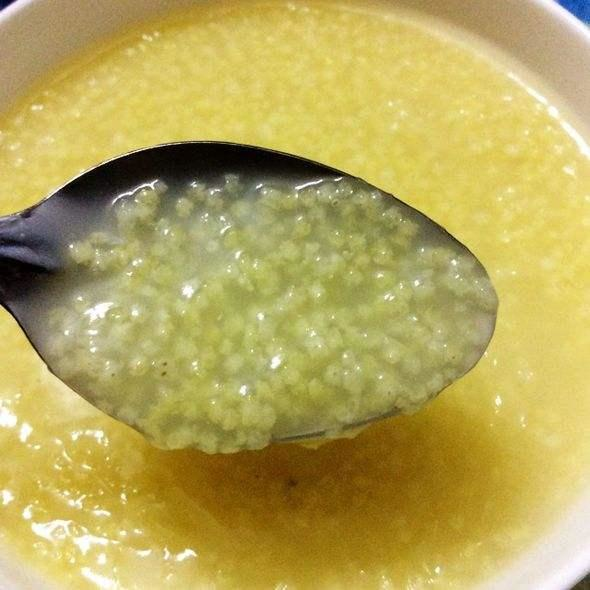 一碗热腾腾的小米粥旁配有一碟切好的金黄色咸萝卜条,旁边放着木勺和瓷碗,体现朴素农家早餐场景 一碗热腾腾的小米粥旁配有一碟切好的金黄色咸萝卜条,旁边放着木勺和瓷碗,体现朴素农家早餐场景