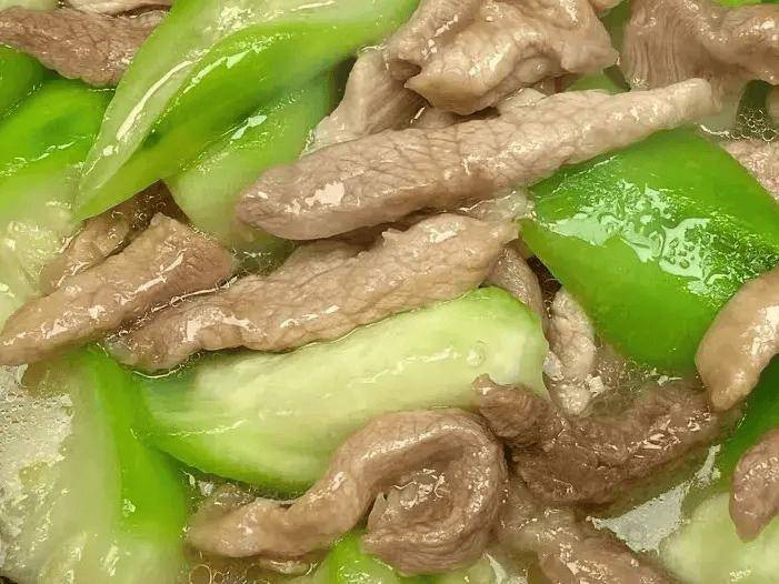 一盘清炒丝瓜配红椒的家常菜肴摆放在木质餐桌上
