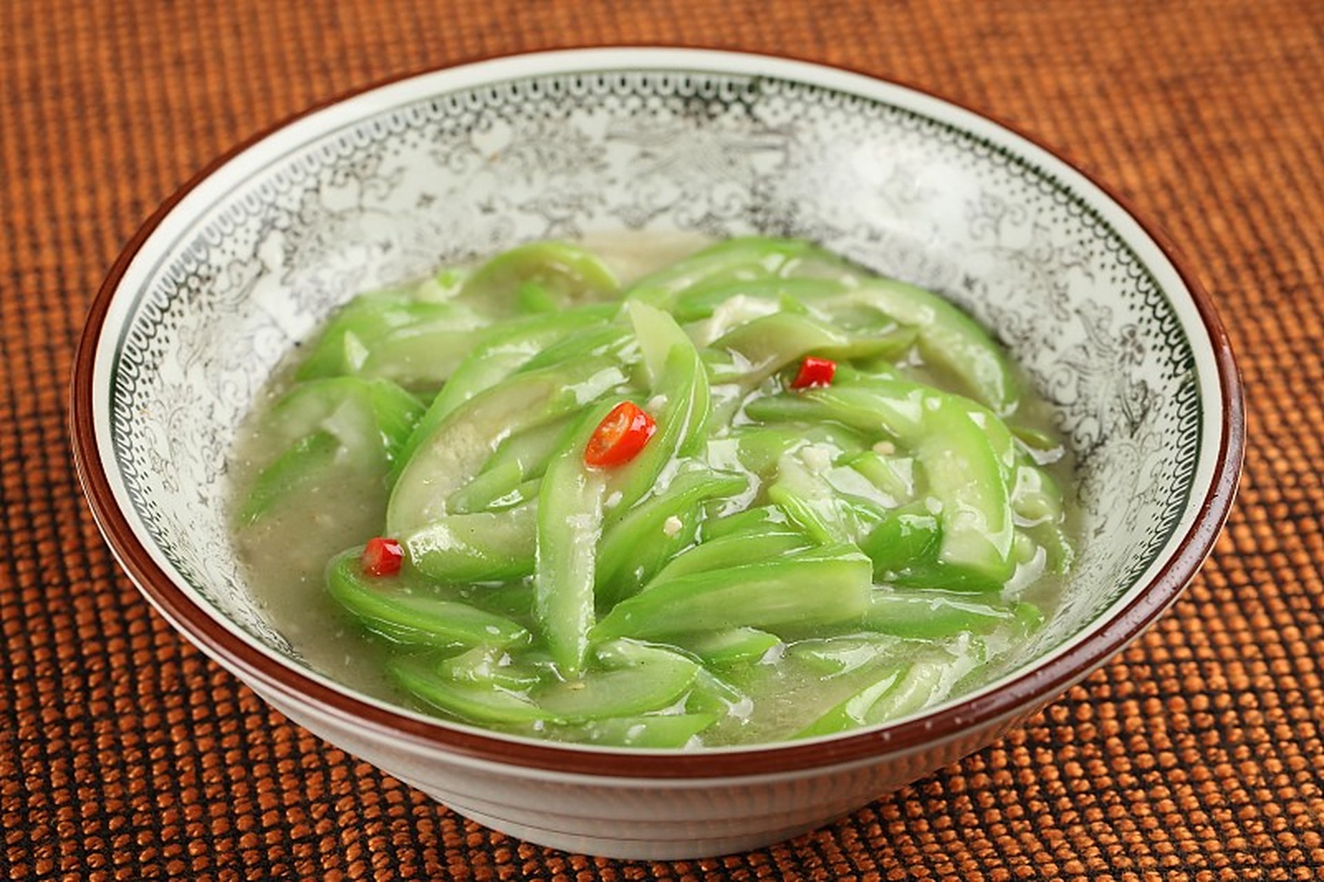 一盘刚出锅的清炒丝瓜豆芽,丝瓜呈淡绿色斜切片,豆芽根部整齐、茎秆挺拔,表面泛着晶莹油光,点缀有红色小米辣和黄色蒜片,盛放在白色瓷盘中,背景虚化 清炒丝瓜豆芽完成菜品特写