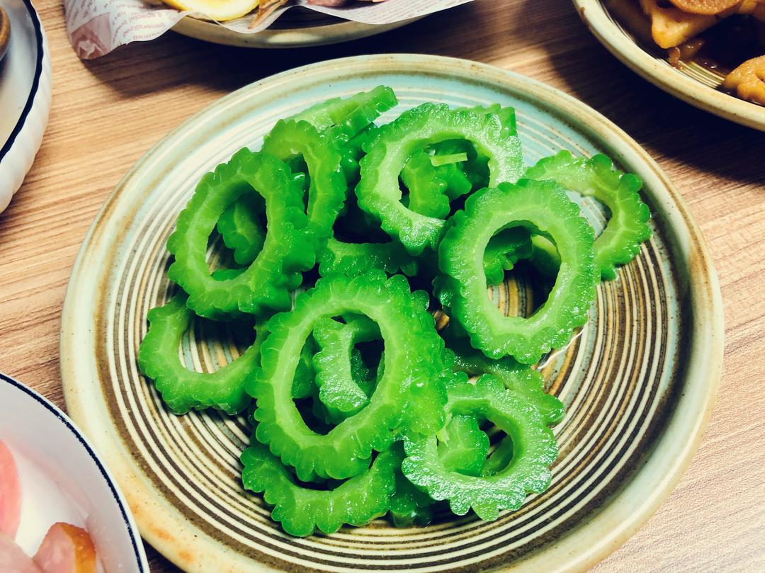 高清微距摄影:左侧为带白霜翠绿苦瓜切段(表皮棱沟清晰),中为浅绿色脆嫩西芹叶柄斜切片(断面纤维束明显),右侧为紫皮洋葱横切片(多层同心鳞片结构分明,边缘略透明,无褐变;背景为竹制砧板,自然光拍摄 苦瓜芹菜洋葱三种新鲜农产品实物特写拼图