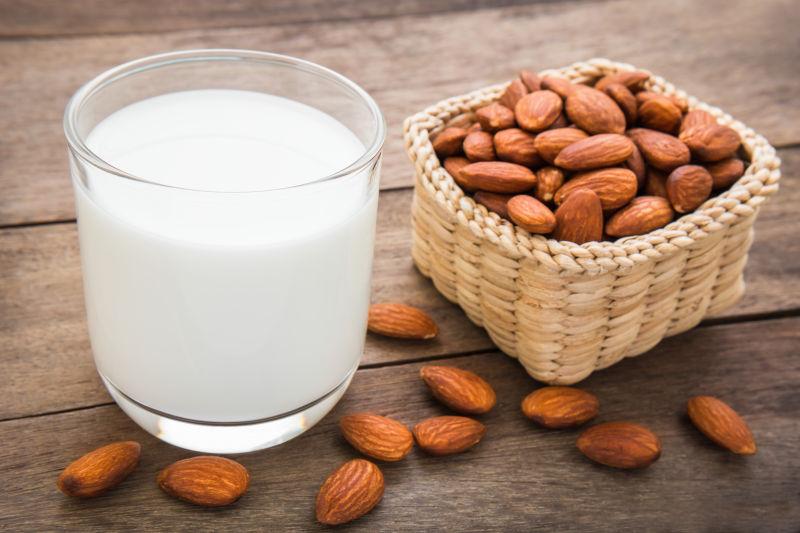 一张健康饮食搭配示意图,左侧摆放一个新鲜库尔勒香梨,右侧配有原味酸奶、一小把杏仁和一片全麦面包,背景为浅色桌布和绿色植物,传达均衡营养的饮食理念 库尔勒香梨与健康饮食搭配图示