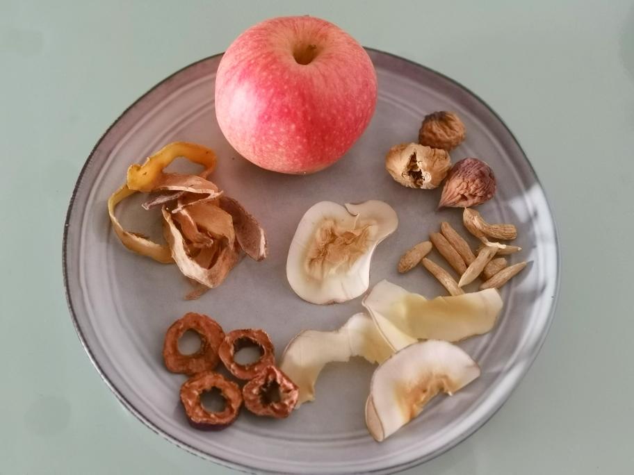 一盘切好的国光苹果片摆放在木质餐盘上,旁边配有少量原味杏仁和核桃仁,背景为厨房台面,体现健康加餐的科学搭配方式 国光苹果切片与坚果搭配