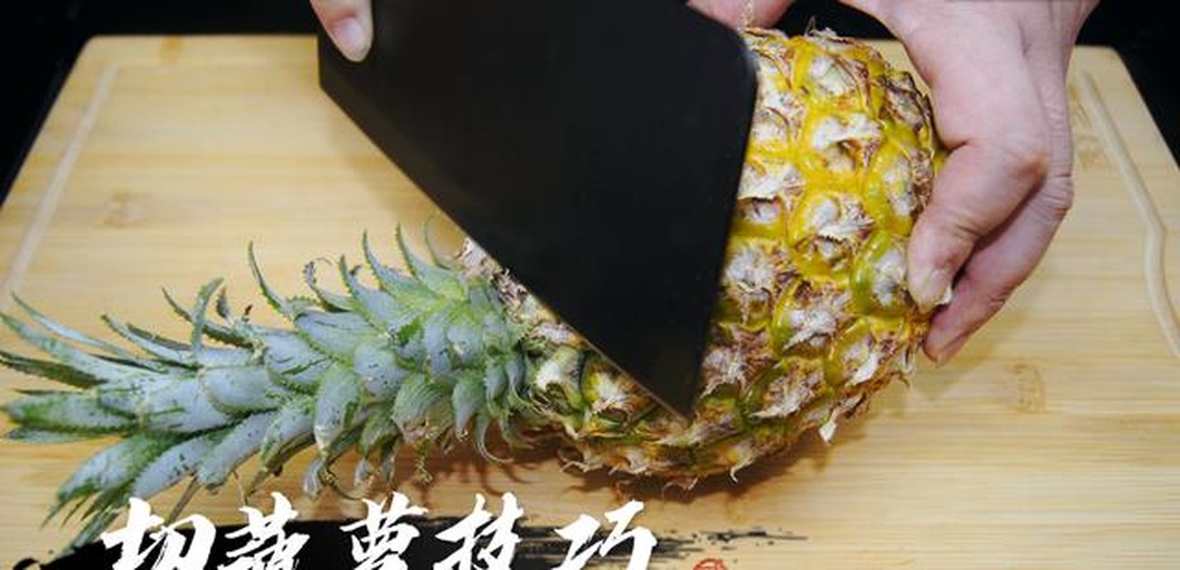 家庭厨房中正在用刀切除菠萝外皮和果眼的场景