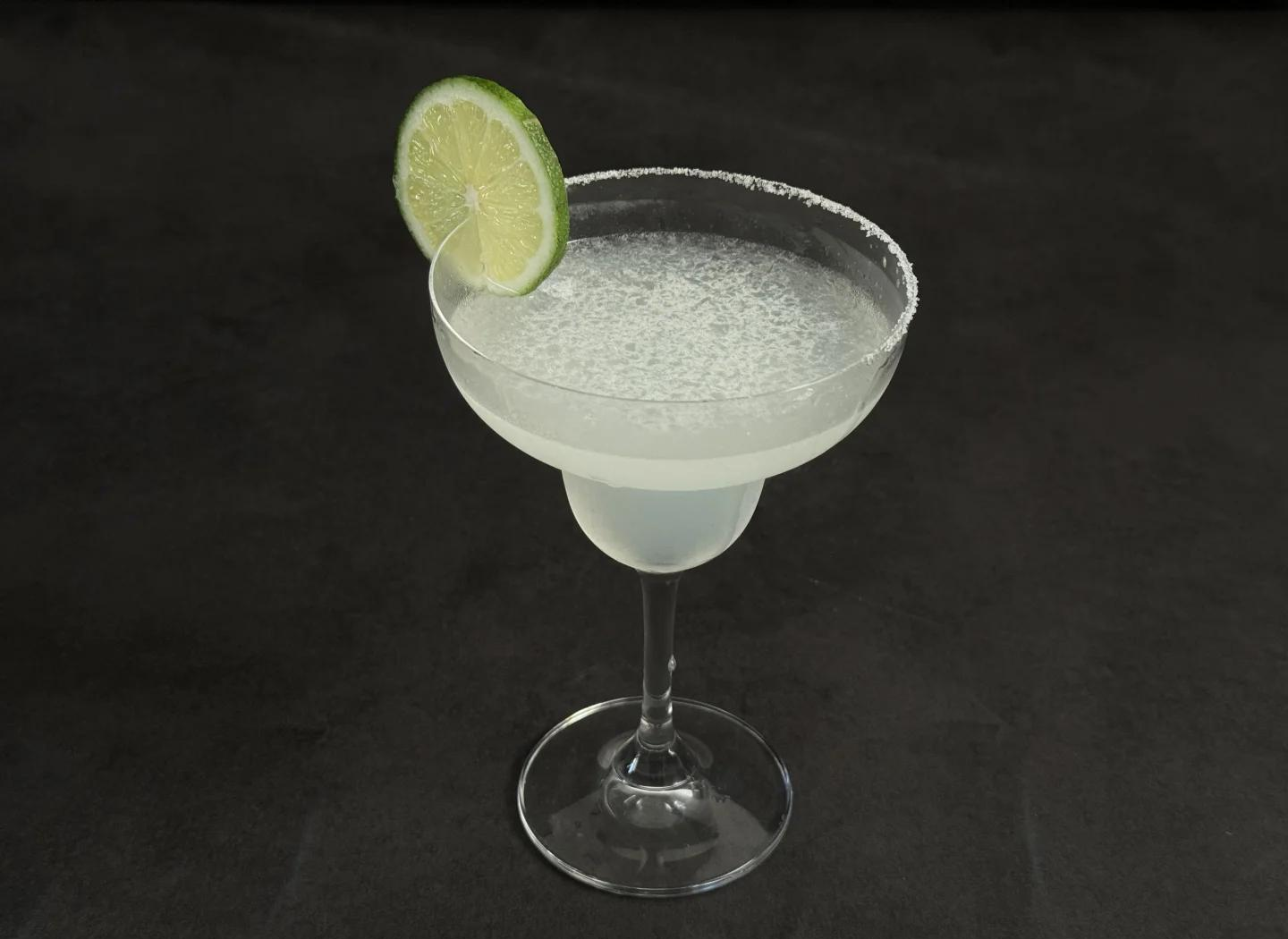 玛格丽塔黄金版高清特写图:霜白色玛格丽塔杯,杯沿覆盖细腻均匀的粗海盐环,杯内为澄澈透亮的浅金色酒液,液面漂浮半颗新鲜青柠角,青柠表皮油亮饱满,背景为暖色调木质吧台与柔和散射光 Margarita黄金版特写:霜白杯沿带均匀海盐环,澄澈浅金色酒液中浮着半颗青柠角,背景虚化木质吧台