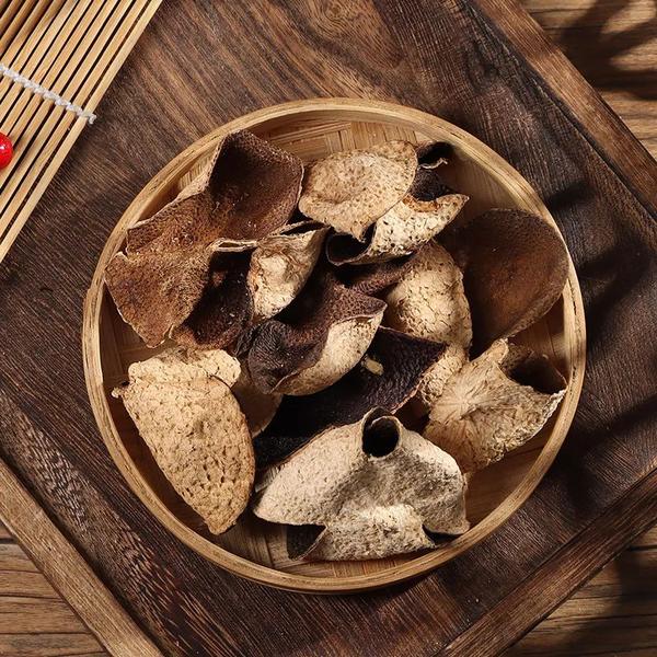传统中药炮制场景:资深药师手持黄铜刮刀,正在处理新鲜冬瓜。画面焦点为刀锋与瓜体接触处——青绿色带厚白霜的冬瓜表皮被均匀刮下,形成薄如蝉翼、微卷曲的翠绿瓜皮碎屑;砧板为纹理清晰的深色榆木,背景虚化中药柜抽屉上贴有毛笔书写的‘冬瓜皮’标签,体现道地药材加工工艺 老药工手工刮冬瓜皮特写:布满白霜的青绿冬瓜置于榆木砧板上,铜制刮刀正从瓜身斜向刮下薄而完整的翠绿瓜皮,皮屑呈半透明卷曲状飘落,背景虚化处可见药柜抽屉标签“冬瓜皮”