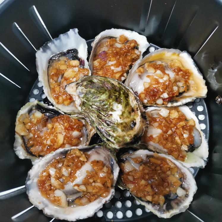 生蚝在炭火上烘烤，表面滋滋冒油，蒜蓉金黄，蚝肉饱满