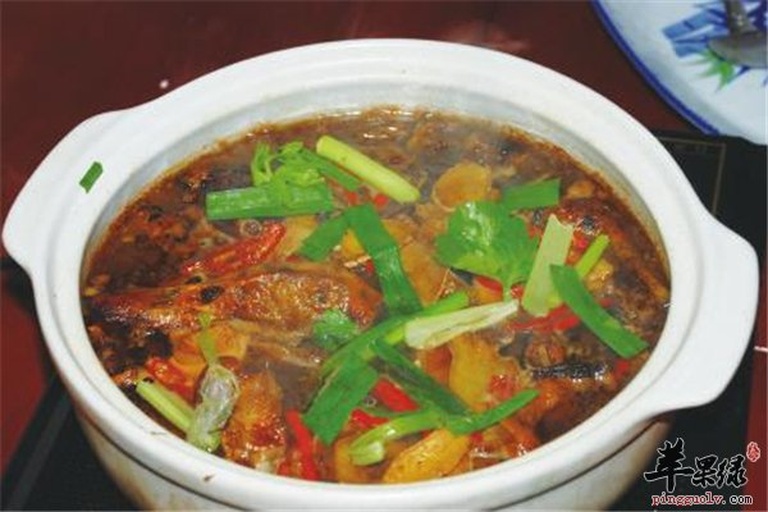 一口黑色砂锅中正在炖煮葱烧豆腐,金黄色的豆腐块浸泡在红亮的酱汁中,周围环绕着大片章丘大葱段,热气腾腾,色泽诱人 葱烧豆腐的烹饪过程