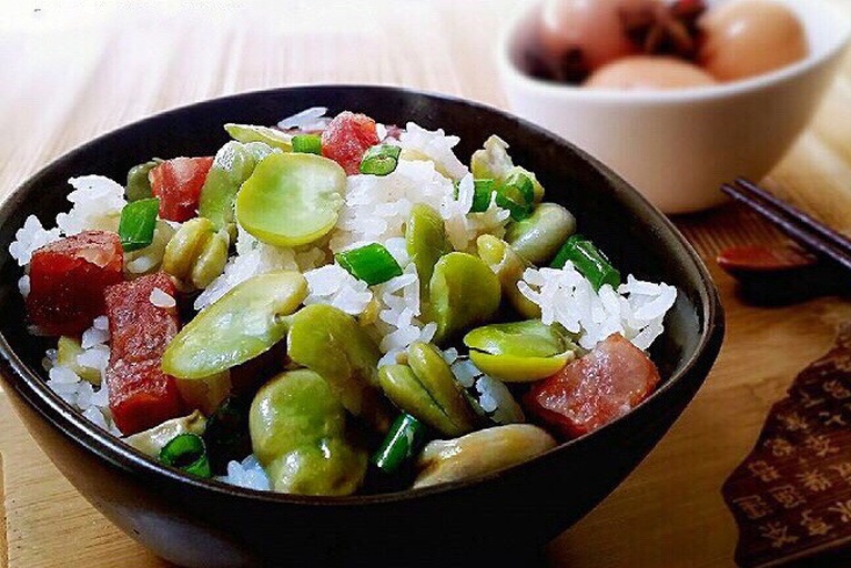 一锅热气腾腾的姬松茸煲仔饭从砂锅中盛出,腊肠红润油亮,姬松茸片分布均匀,米饭粒粒分明带有光泽,表面撒有翠绿葱花,锅底可见焦黄色锅巴,背景为深色木质餐桌,氛围温馨 姬松茸煲仔饭成品俯拍图