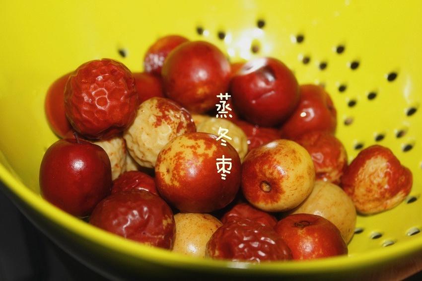 蒸红枣出锅特写：青花瓷盘中盛放12颗琥珀色蒸红枣，表面油润微光，部分去核枣露出金黄果肉，旁置枸杞与陈皮点缀