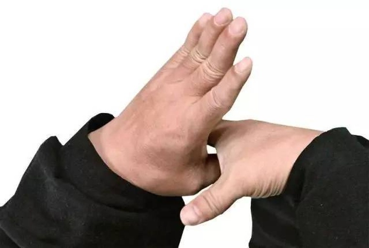 手部特写图：一只手托起两颗沃柑对比重量，另一只手拇指正轻压左侧沃柑果皮测试弹性，背景虚化突出触感细节