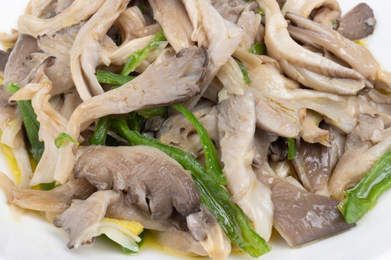 平菇炒青椒烹饪过程特写 平菇与青椒在炒锅中翻炒的特写画面,锅中食材色泽鲜亮,平菇呈乳白色,青椒为翠绿色,表面略有油光,灶火正旺