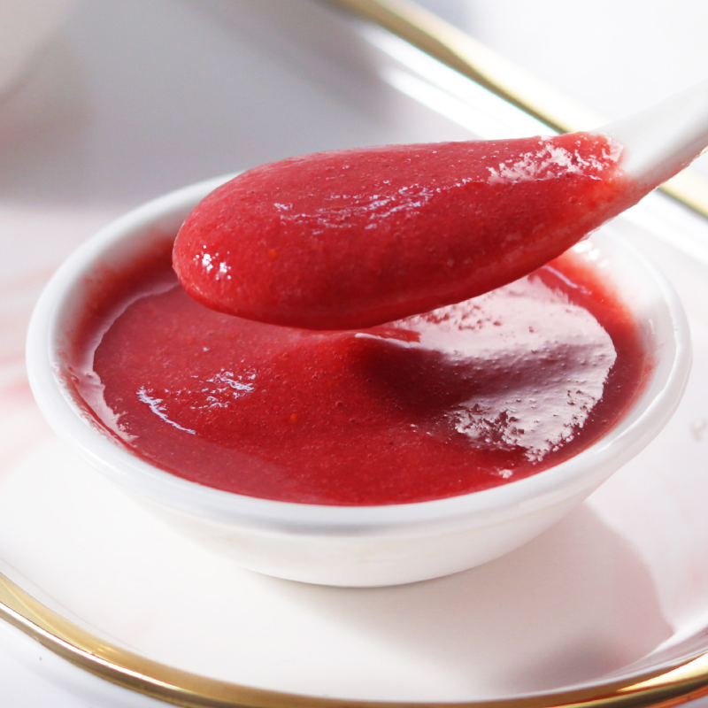 近景特写画面:一只手拿着勺子正在将紫红色的蓝莓酱均匀涂抹在一瓣切开的白色馒头切面上,酱体细腻带有果粒,光线柔和,突出操作细节与食物质感 蓝莓酱涂抹过程特写