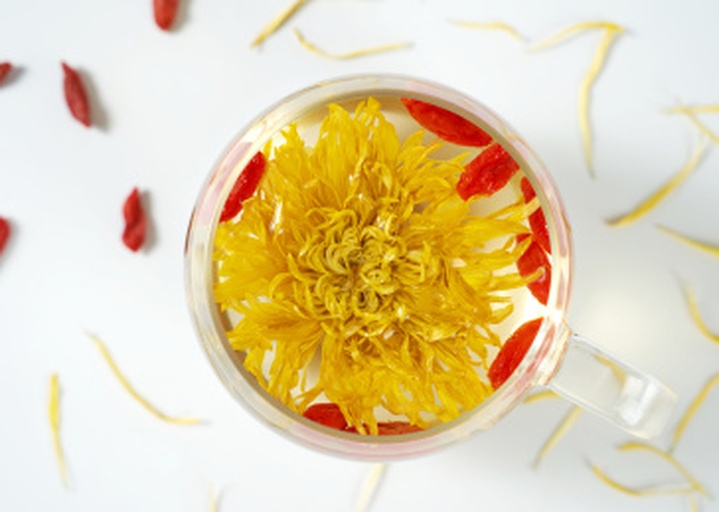 生活化场景摄影:德国洋甘菊(Matricaria chamomilla)冲泡茶饮,展示标准冲泡形态——清澈淡金色汤色(L*值>75),悬浮细微花粉颗粒,杯壁附着薄层油性光泽(源自挥发油),佐以柠檬片提升槲皮素生物利用度,体现农产品科学食用方式 德国洋甘菊茶饮实景:透明玻璃杯中盛放淡金色茶汤,杯底沉淀少量金黄色花蕊碎屑,杯沿放置半片新鲜柠檬与一枝带露水的洋甘菊鲜枝,桌面铺亚麻布,突出农产品到饮品的转化过程