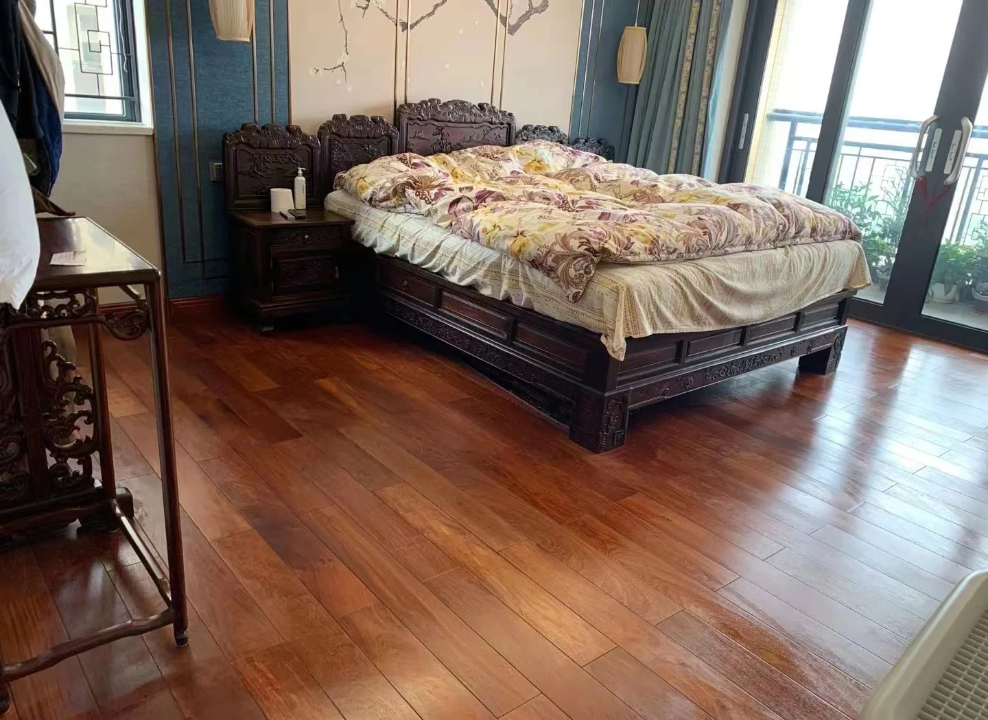 一间中式风格客厅内铺设的金花梨实木地板,光线照射下呈现出流动的金色纹理,地板拼接为人字形图案,边缘收口精细,整体质感沉稳奢华 铺设完成的金花梨地板实景图,展现其温暖光泽与细腻纹理