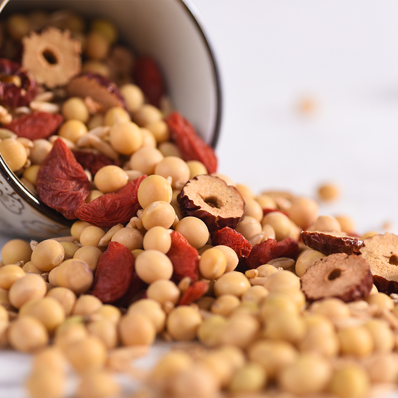 厨房场景中正在用铜锅炒制油栗仁,锅中油栗仁微微裂开露出金黄内仁,旁边摆放着竹篮装的新鲜花生与红枣,体现传统滋补食材搭配氛围 油栗仁烹饪场景