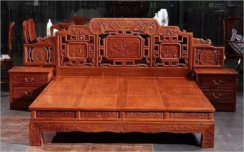 一件手工雕刻的金花梨罗汉床局部特写,展示精细的云纹雕花与打磨光滑的表面,木材呈现出金黄色调与深色条纹交织的纹理,光影下泛出丝绸般光泽,旁边放置一把木工刨刀作为工具参照 手工雕刻的金花梨家具细节