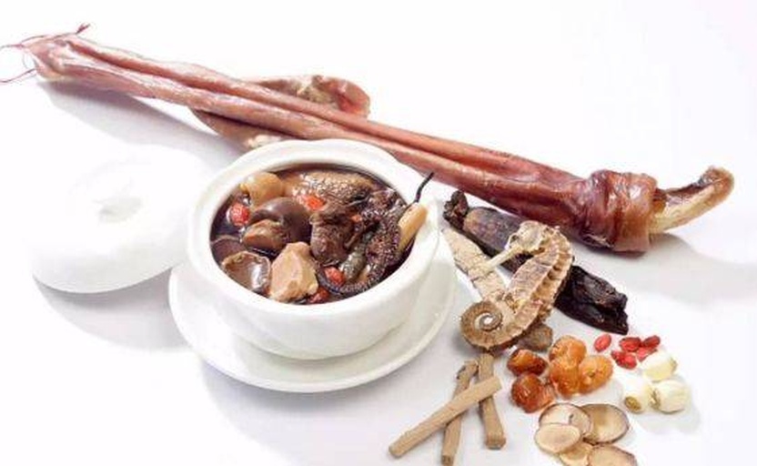 一碗清澈金黄的汤品放置在深色木质餐桌上,汤面微微油光,可见完整的海马形态和几片生晒参,旁边点缀枸杞和红枣,整体呈现高端养生美食风格,光线柔和,突出食物质感 成品海马炖生晒参汤盛在瓷碗中的特写