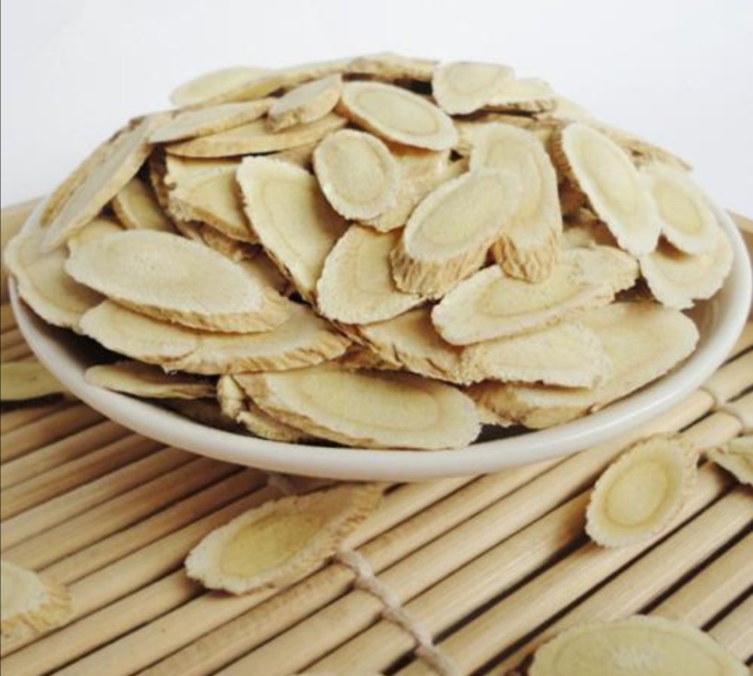 高清特写图:左侧为切片后的淡黄色黄芪饮片,表面有明显纵皱纹,质地坚韧;右侧为深棕红色的新会陈皮,油室密集可见,卷曲成片状,背景为木质托盘,自然光下拍摄,突出中药材天然质感 黄芪与陈皮药材特写