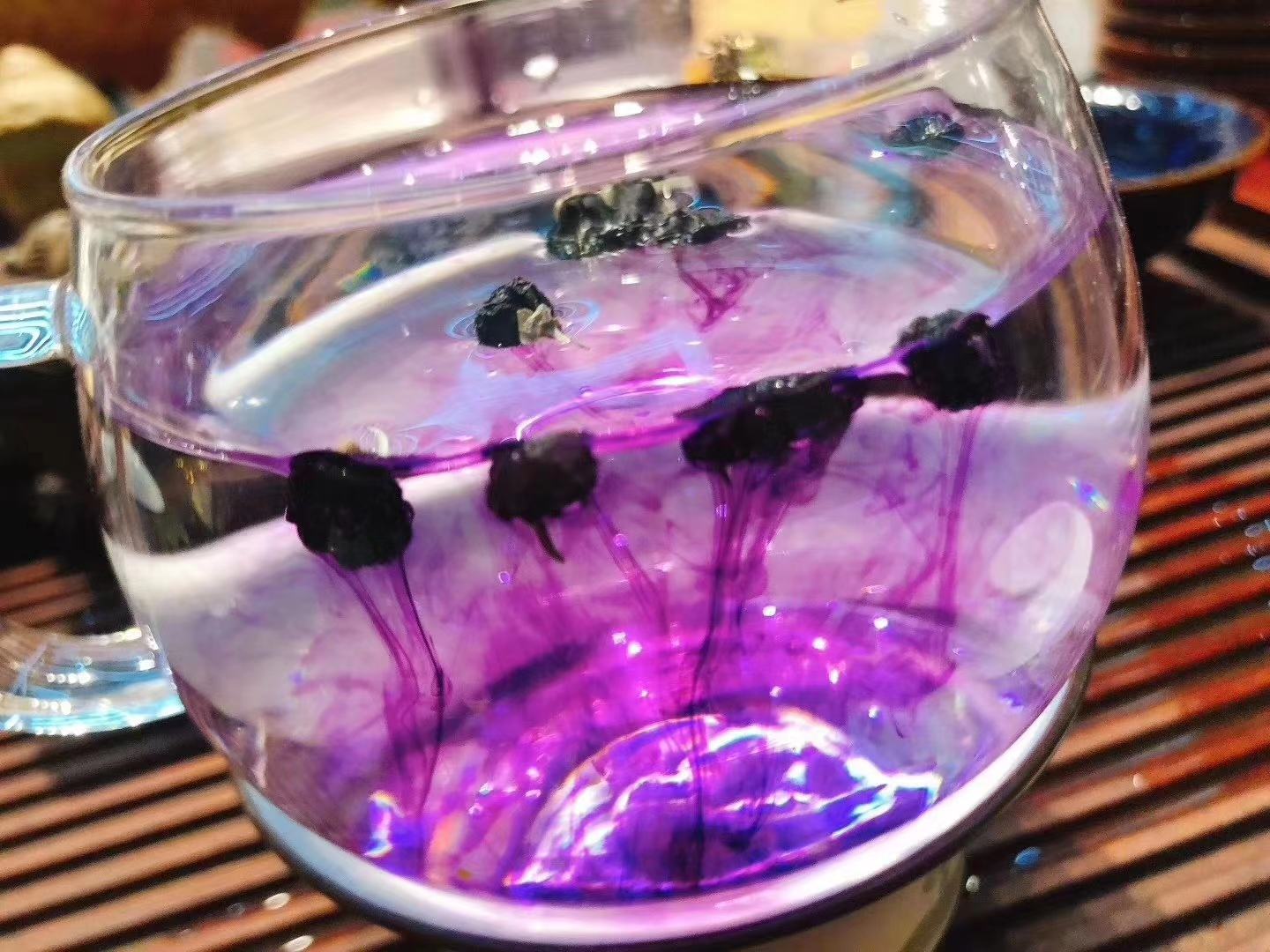 黑枸杞泡水图,展示其在水中释放出的深紫色液体,背景为玻璃杯和枸杞干果 黑枸杞泡水图