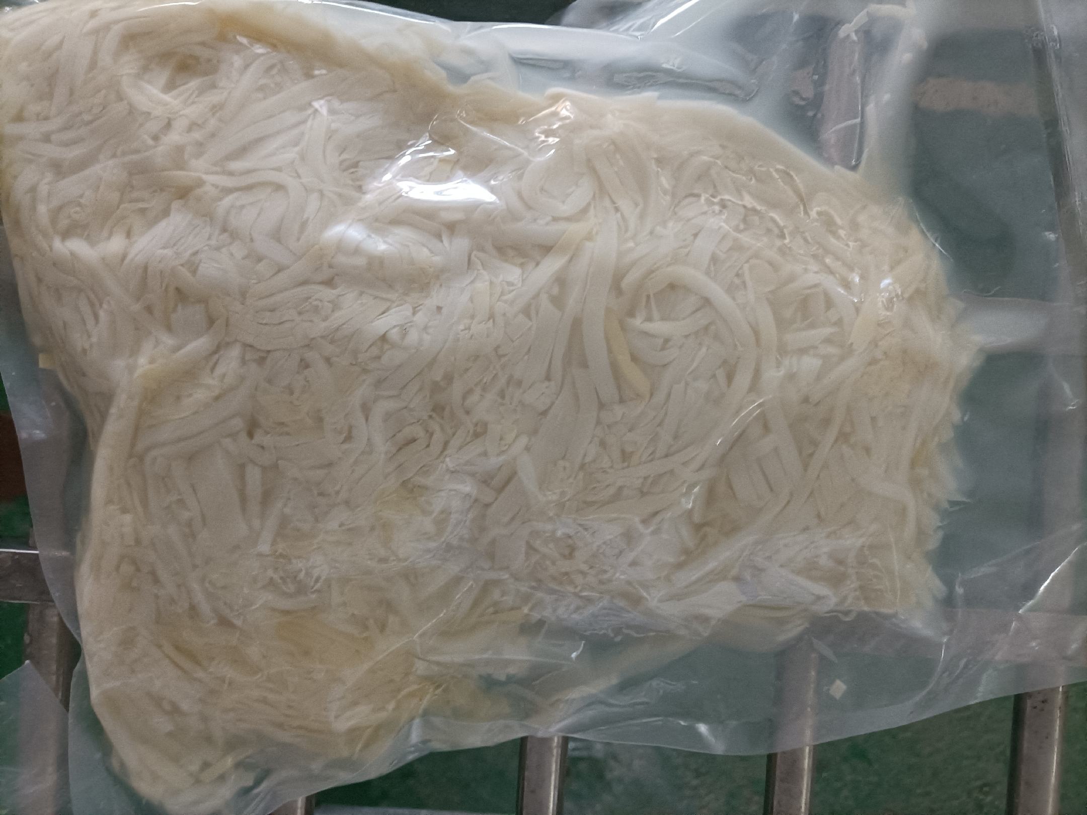 家庭厨房场景：年轻女性用锋利厨刀将新鲜结球生菜切成细丝，置于陶瓷碗中，背景可见冰箱门上贴着手写便签：“每日生菜150g ✅”，台面放有食品级电子秤与《中国居民膳食指南2022》开页