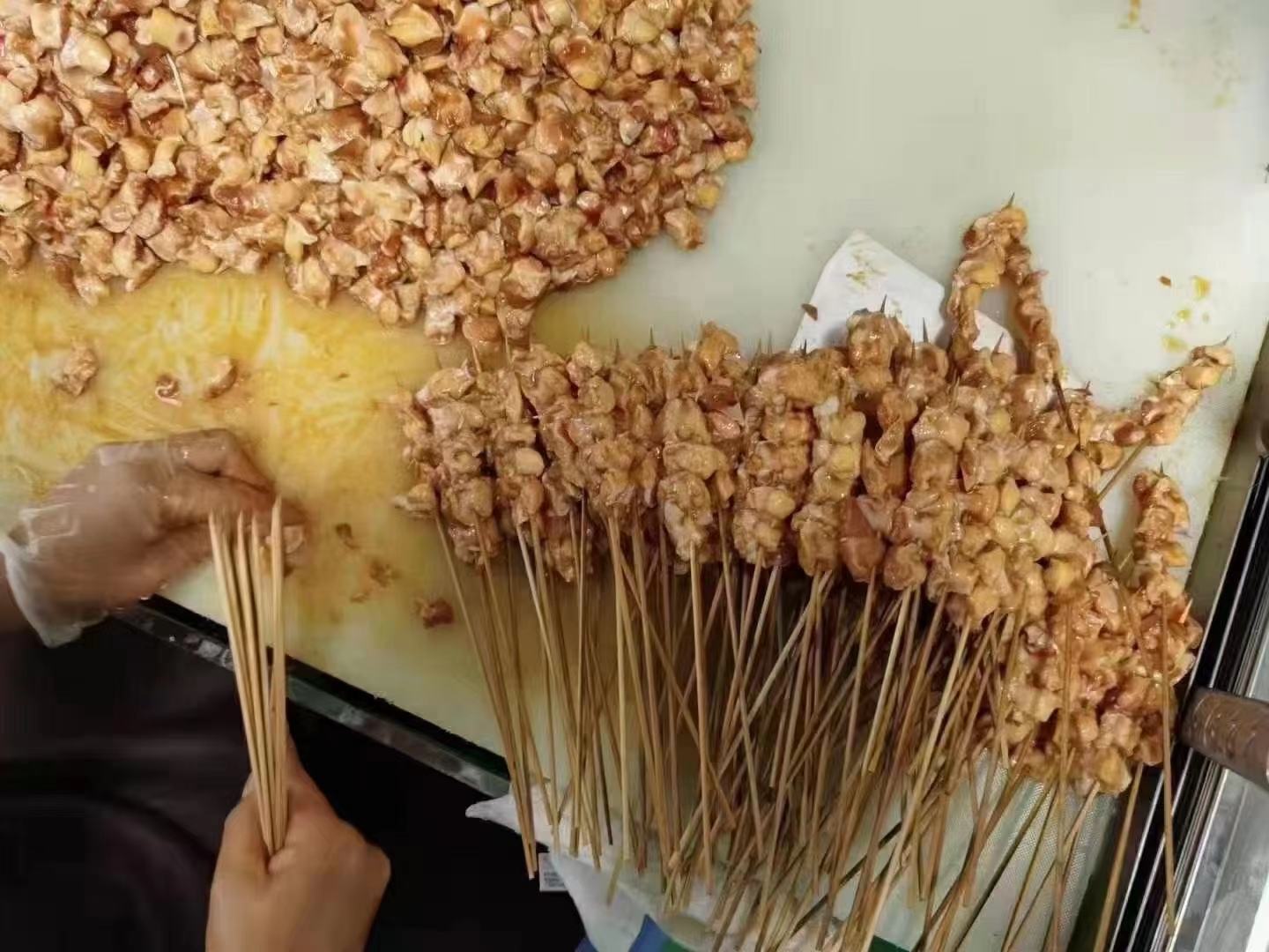 京葱鸡腿肉串穿串过程展示，鸡肉与京葱交替穿在竹签上的细节