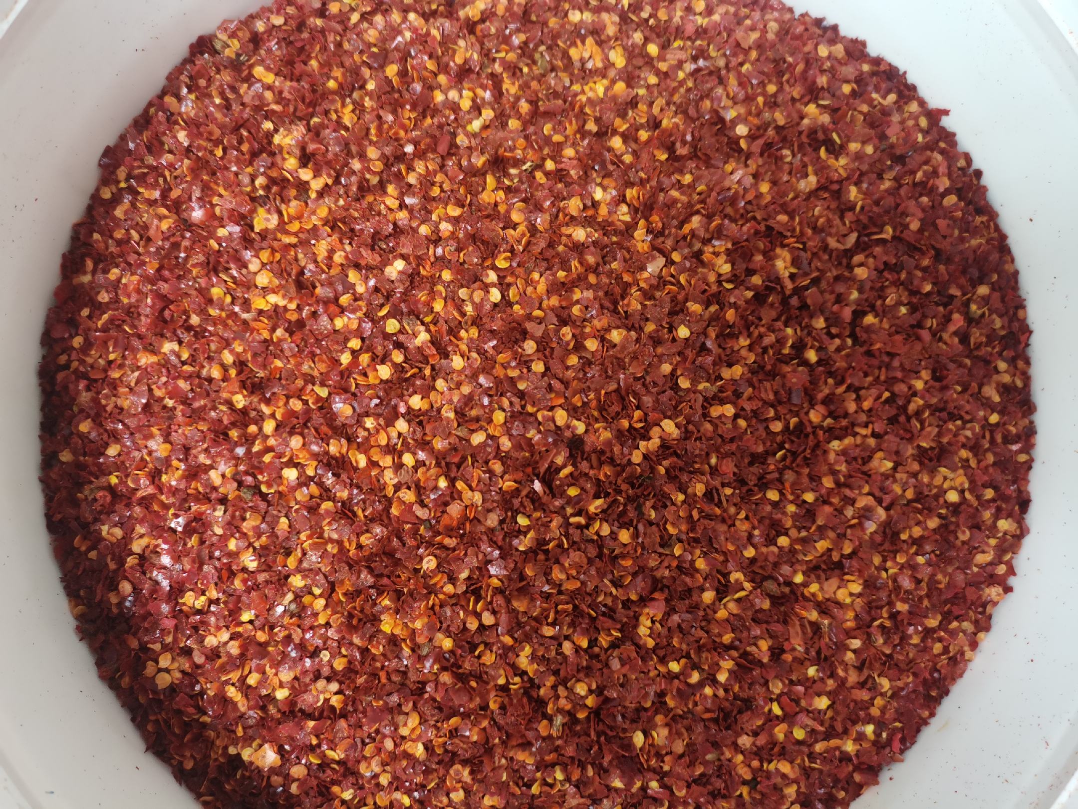 近距离拍摄一碗泡发后的白辣椒,呈米白色至浅褐色,表面有明显褶皱,部分已回软,旁边配有整颗未泡发的干制白辣椒,背景为木质案板和陶制调料罐,展现传统厨房质感 白辣椒成品特写