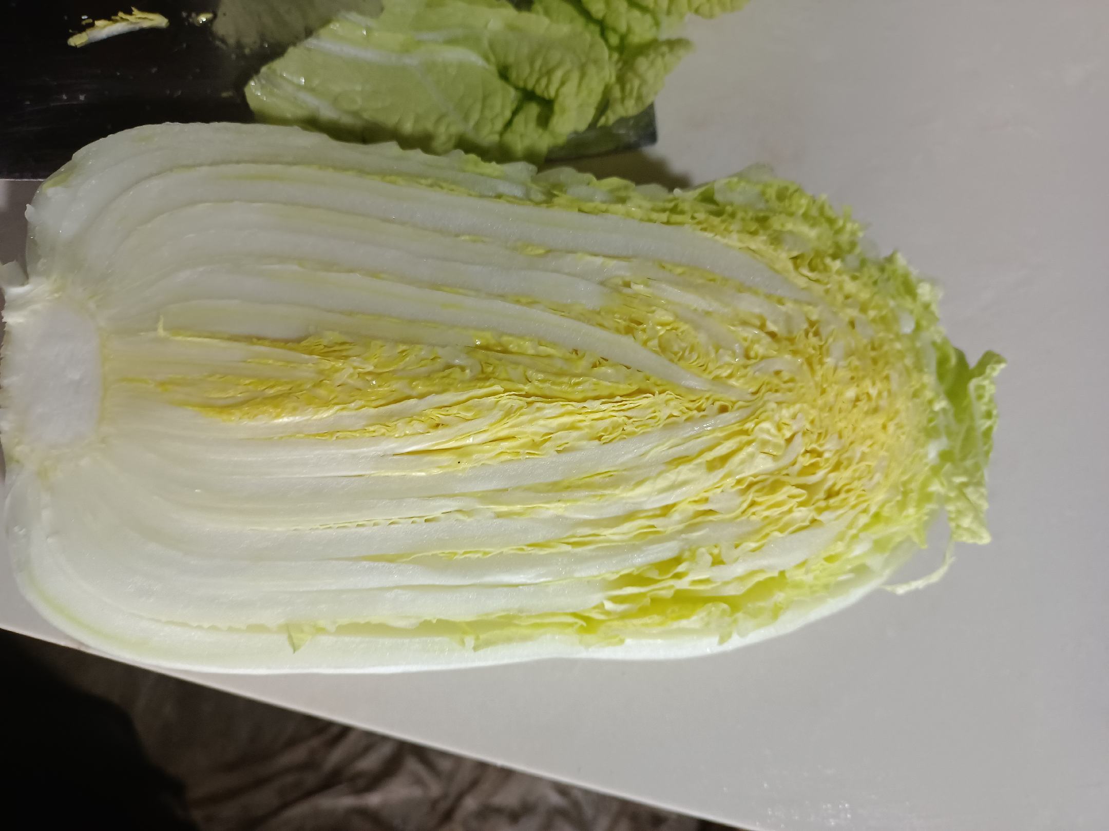 展示一整颗新鲜娃娃菜,叶片紧实、色泽鲜嫩,背景为厨房或市场环境 新鲜娃娃菜展示图