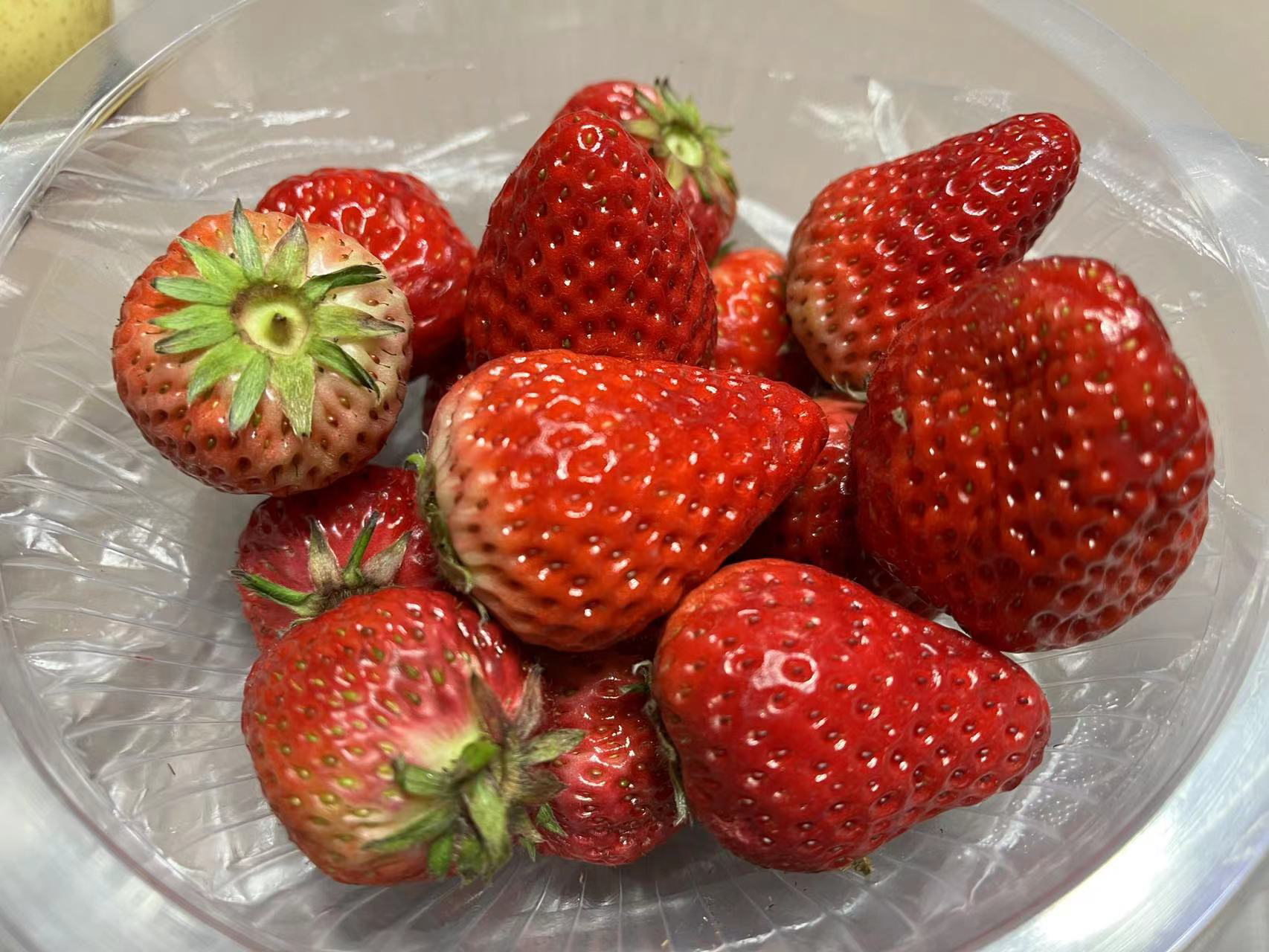 一杯装在透明玻璃杯中的草莓香蕉冰沙,表面撒有香草粉,旁边摆放着新鲜草莓和香蕉片作为装饰 草莓香蕉冰沙成品图