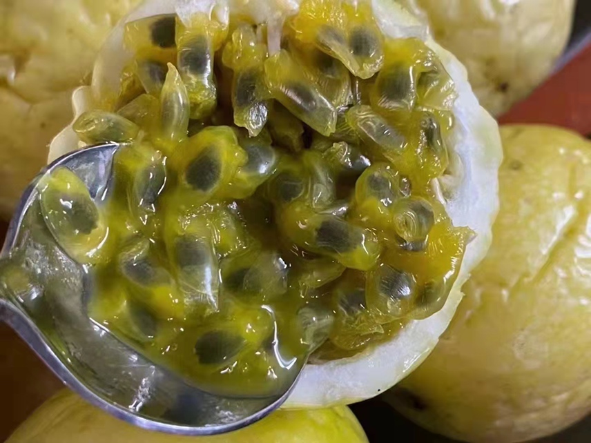 剖开的百香果,露出内部多汁的果肉和黑色种子,背景为厨房操作台 百香果切开图