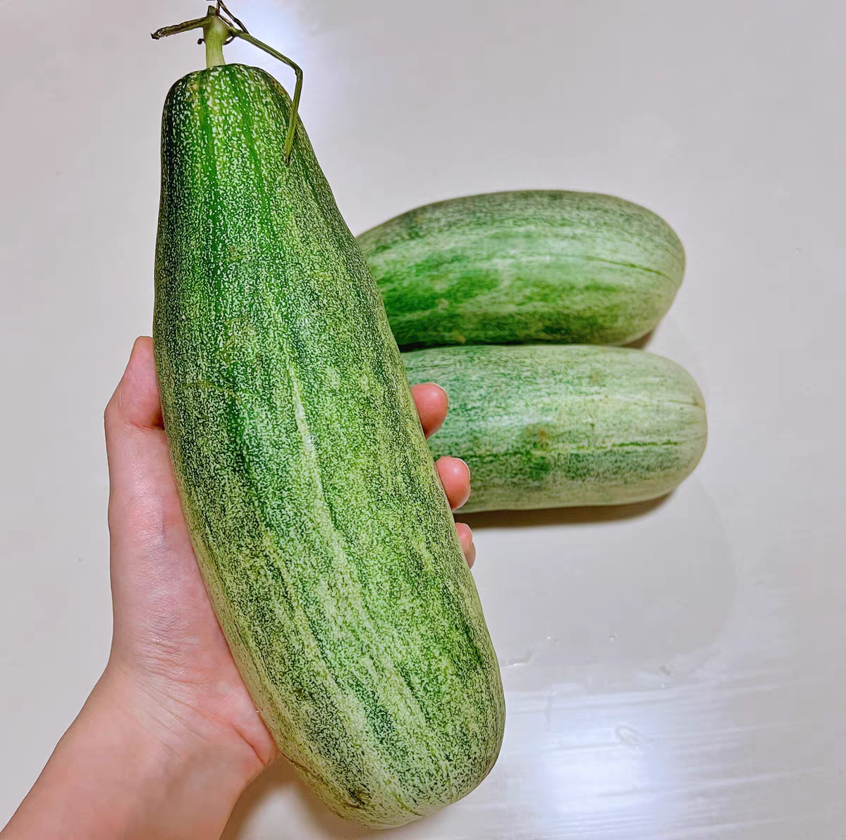 展示一颗完整新鲜的羊角蜜甜瓜,表面带有自然纹理和绿色条纹 羊角蜜甜瓜外观特写