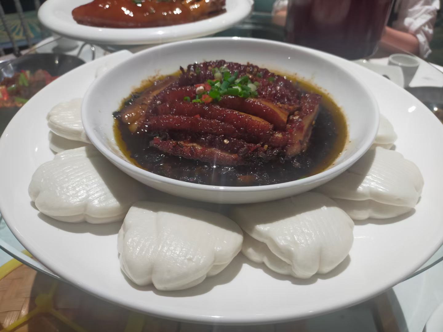 成品全景图:一盘浅色陶瓷碟中摆放着三块热腾腾的蒸馒头,切面透出淡淡的紫红色蓝莓酱痕迹,表面撒有少量白芝麻,旁边配有半杯牛奶和一把木勺,背景为清晨阳光照射的厨房窗台,营造温馨早餐氛围 蓝莓酱蒸馒头成品展示